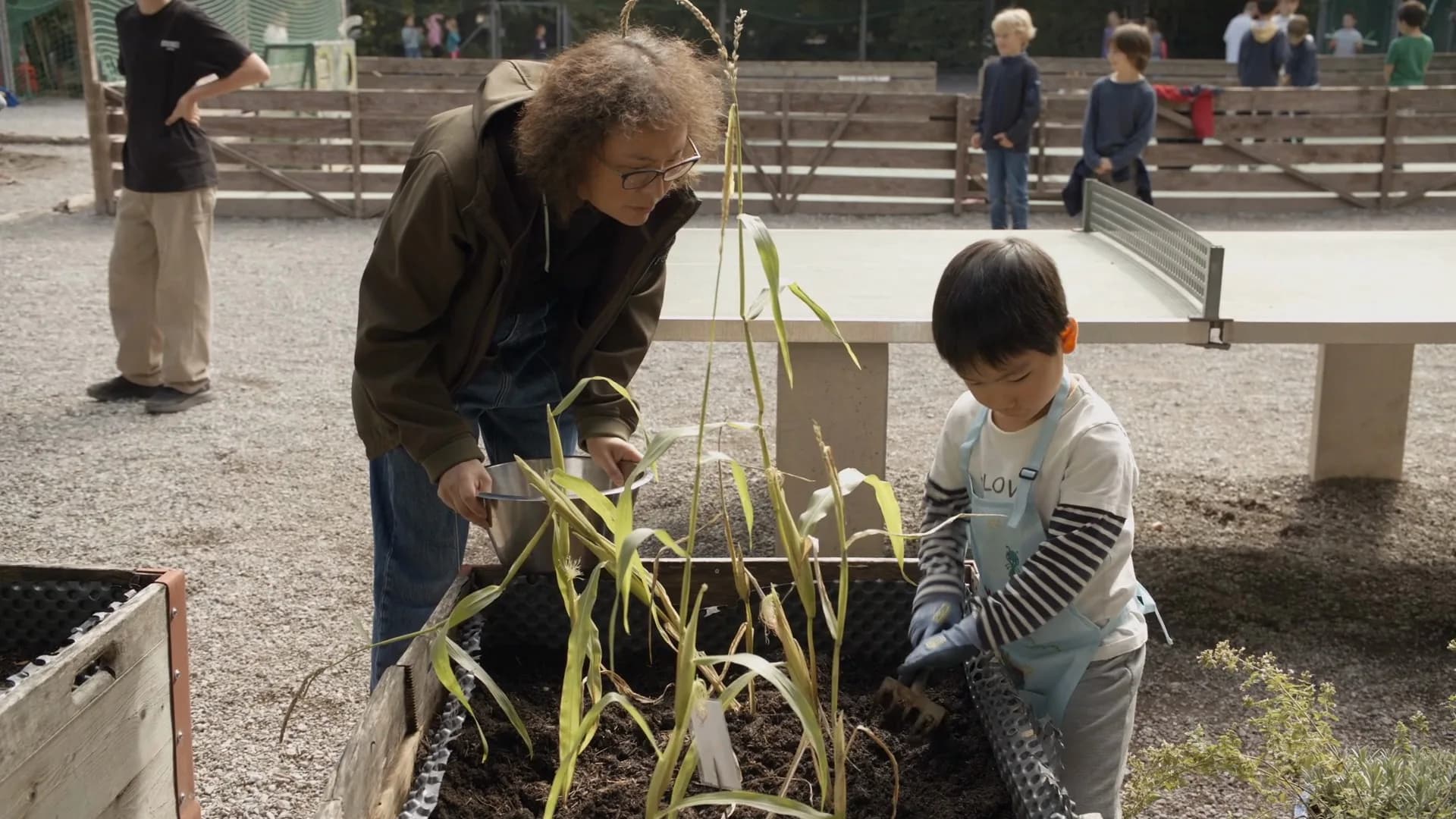Lehrperson und Kind bei der Gartenarbeit im Pausenhof